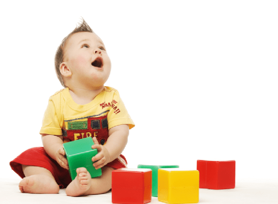 Baby in yellow shirt playing with blocks looking up surprised