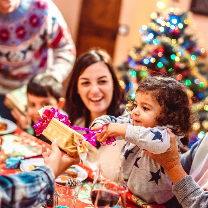 children opening gifts by christmas tree