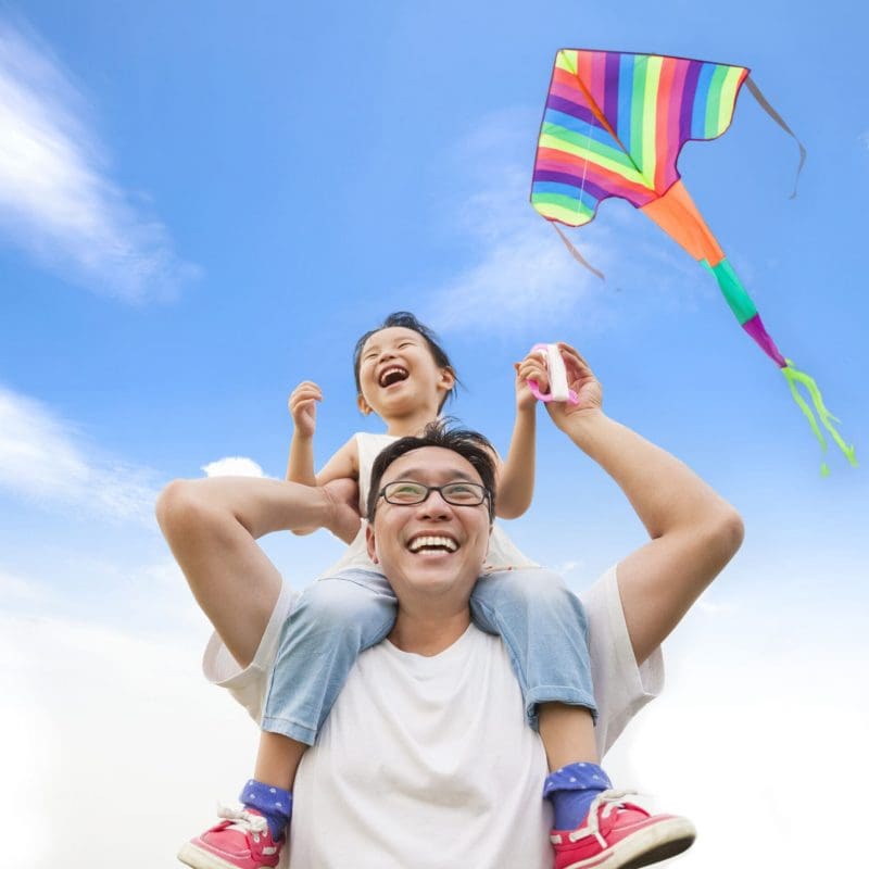 happy little girl on his father shoulder with colorful kite